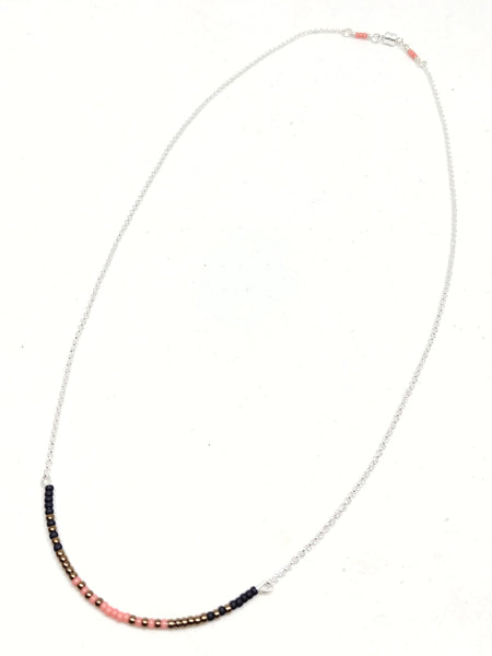 Ready To Rise Necklace: Sterling Silver chain featuring focal piece with seed beads in salmon, black and bronze.
