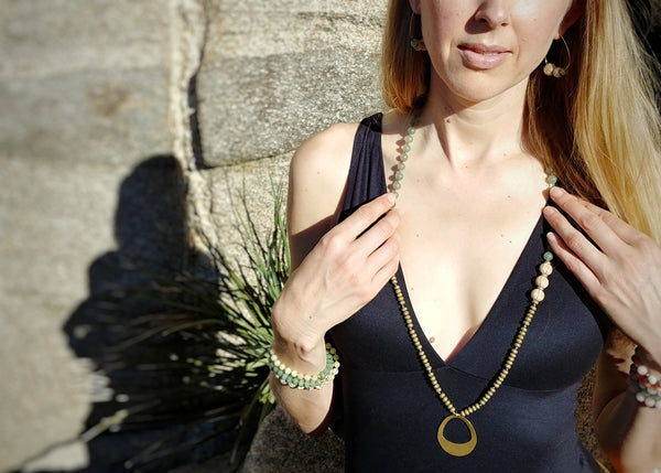 Model wearing Palm Canyon Necklace, 33" mala-style knotted necklace, aventurine, hematite and sandal wood, brass oval pendant