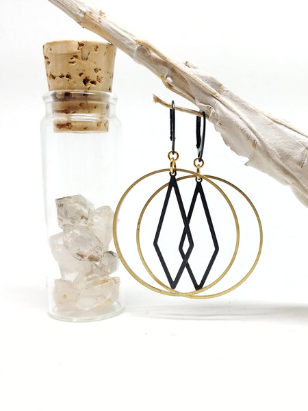 Diamond Hoops featuring black oxidized brass lever-back ear wires and oblong diamond inside of a raw brass hoop, 65mm top to bottom. Shown hanging.