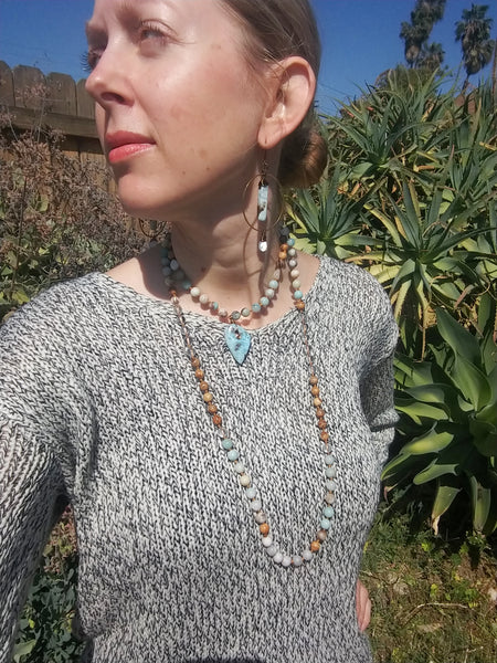 Model wearing Larimar Mala Necklace doubled up with pendant at choker length, paired with Calming Waters Earrings.