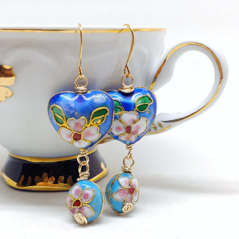 Gold dangly cloisonné bauble earrings featuring vibrant blues and daisy motifs.