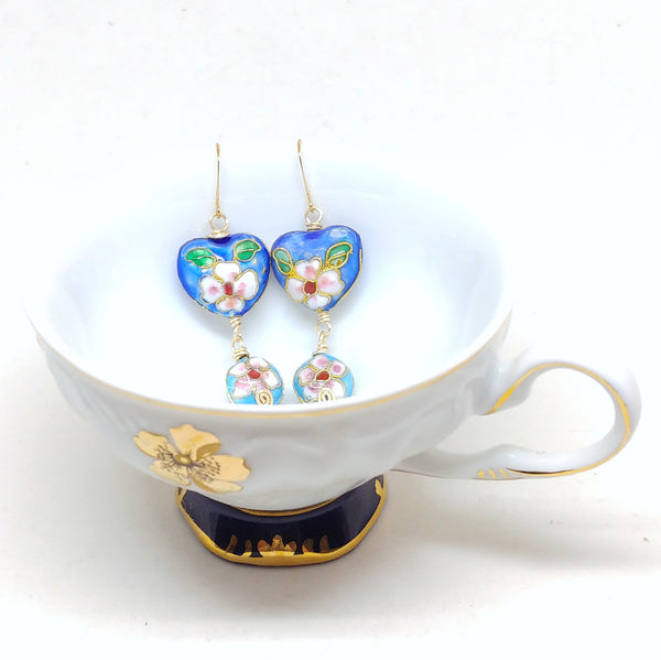 Gold dangly cloisonné bauble earrings featuring vibrant blues and daisy motifs.