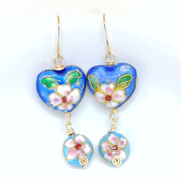 Gold dangly cloisonné bauble earrings featuring vibrant blues and daisy motifs.