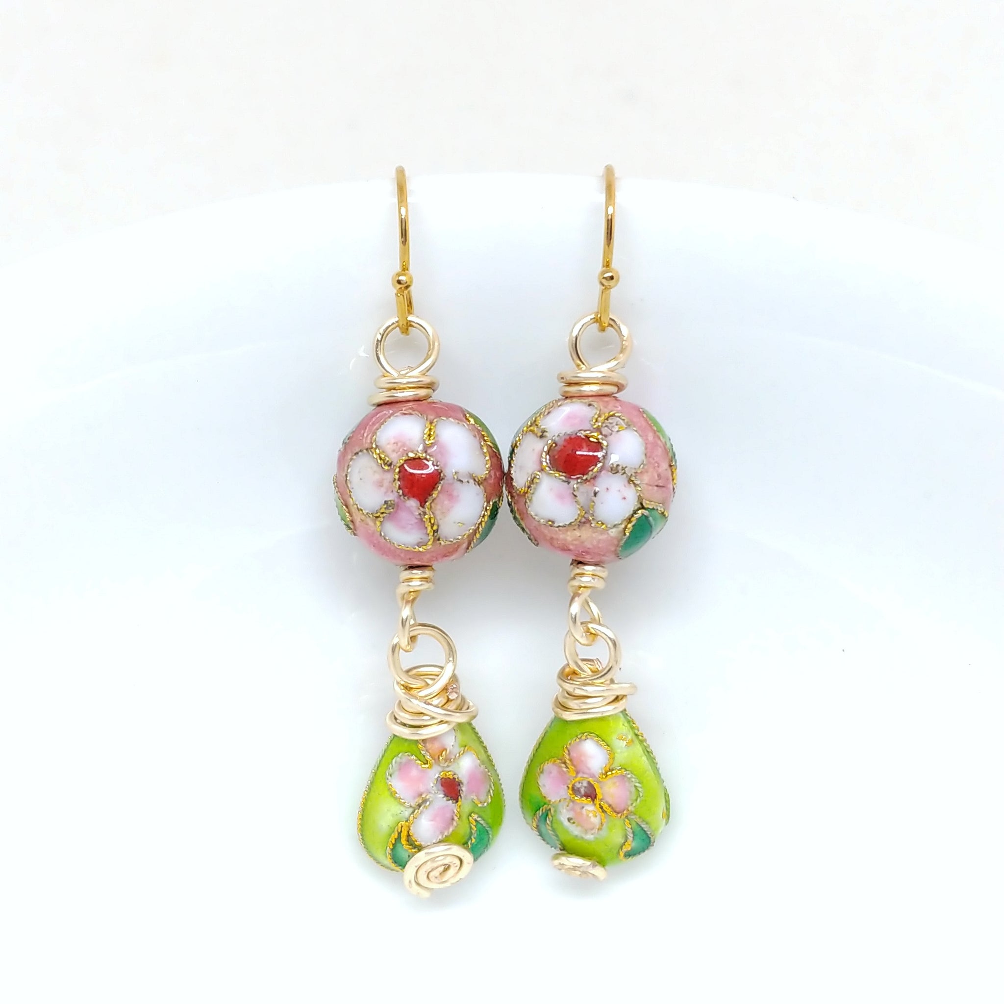 Gold dangly cloisonné bauble earrings featuring vibrant pinks and greens with daisy motifs.