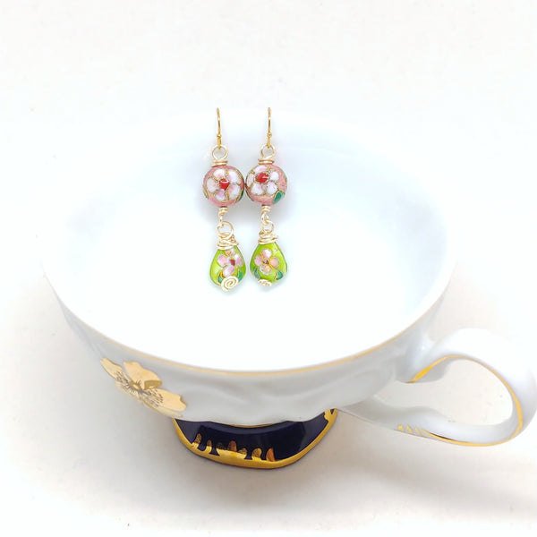 Gold dangly cloisonné bauble earrings featuring vibrant pinks and greens with daisy motifs.