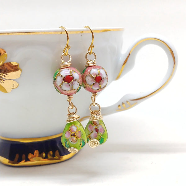 Gold dangly cloisonné bauble earrings featuring vibrant pinks and greens with daisy motifs.