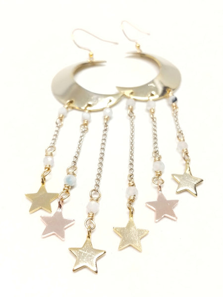 Large gold crescent moon earrings with shiny stars dangling from underneath by silver chain and moonstone accents.
