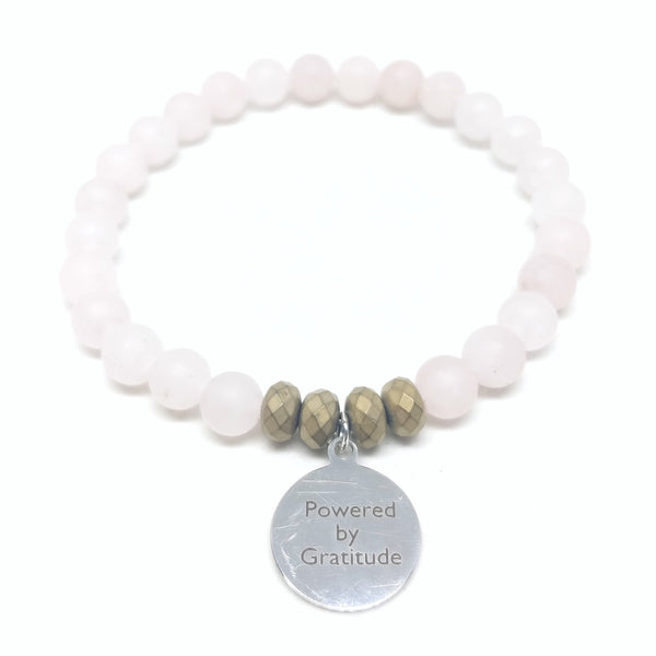 Mother's day stretch charm bracelet in matte rose quartz with stainless steel "Powered By Gratitude" charm.
