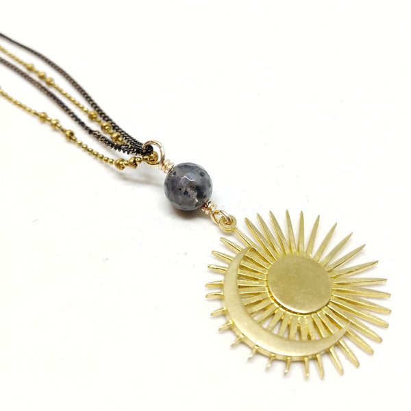 Close up of larvikite and brass sun and moon pendant.